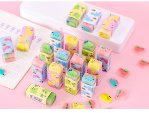 Flat lay of colorful dinosaur jelly erasers scattered on a pink surface with stationery