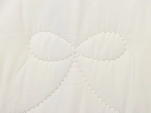 Detail shot of elegant quilted bow pattern on cream white fabric with fine stitching