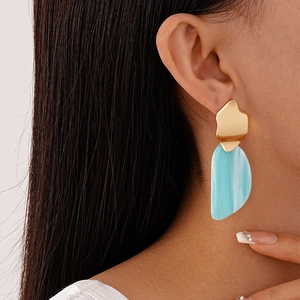 Détail de boucles d'oreilles en acrylique bleu clair avec clous dorés sur mannequin