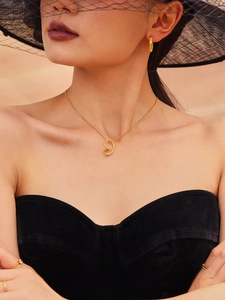 Model wearing a gold hollow heart pendant necklace with matching rings in a desert setting