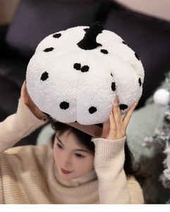 Close-up of white plush pumpkin pillow with black polka dots and soft textured fabric