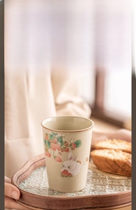 Detailed view of handmade Ru Kiln ceramic cup with rabbit and strawberry patterns