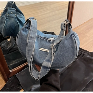 Detail of vintage blue denim crescent bag featuring fashion label and adjustable strap