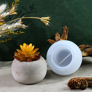 Détail montrant le moule en silicone rond à côté d'un pot de fleurs texturé en pierre