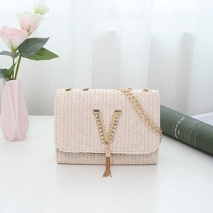 Women's cream woven crossbody bag with gold V-logo and fringe tassel on white table