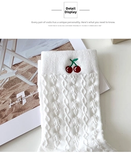Close-up of white cable knit sock detailing with a delicate red cherry embroidery