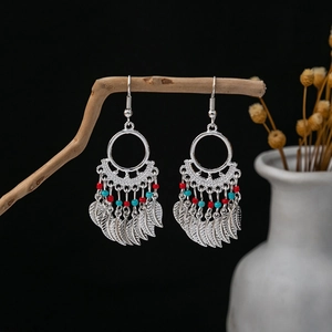 Detail of Bohemian leaf tassel earrings with red and blue beads on a branch