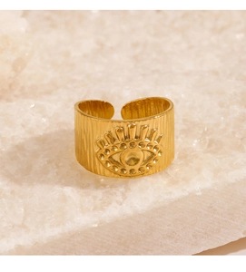 Vue détaillée d'une bague œil maléfique dorée avec texture gaufrée sur socle en cristal