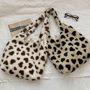 Detail of plush heart-pattern tote bags with soft faux fur texture and metal buckle