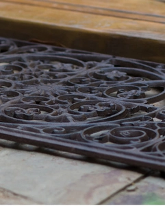 Dettaglio dello zerbino vintage in ghisa con intricati motivi floreali a volute