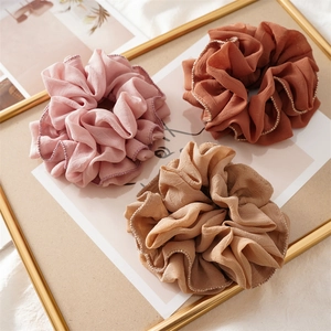 Detailed view of pink, brown, and khaki fabric scrunchies with elegant gold trim edges