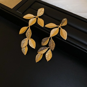 Macro shot of gold leaf tassel earrings showing metallic textures and leaf vein details