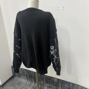 Close-up of white skeleton bone jacquard patterns on black knit sweater sleeves