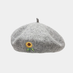 Close-up of sunflower embroidery detail on grey wool felt beret for a vintage style