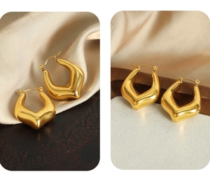 Detail of gold U-shaped geometric earrings on silk and textured white background