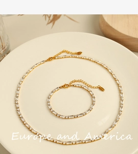 Detail of gold jewelry set featuring a tennis necklace and bracelet with zircon crystals