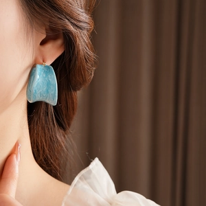 Macro detail of French vintage blue marble resin earring on model with golden post