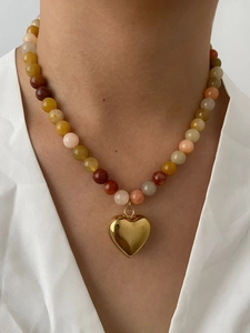 Detail of colorful natural stone beads with a polished gold heart pendant necklace
