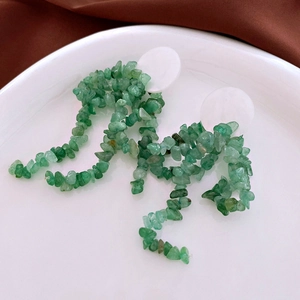 Detail of elegant drop earrings featuring white round studs and green natural stone chips