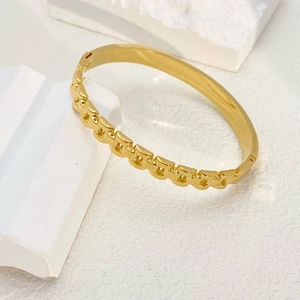 Detailaufnahme eines goldenen Gliederketten-Armbands aus Titanstahl auf weißem Gipsblock