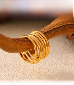 Close-up of PVD gold plated geometric rings on wood showcasing smooth electroplated finish