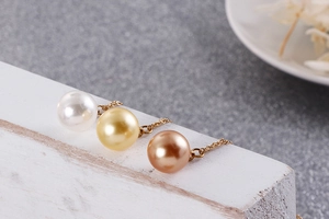 Gros plan de trois perles élégantes en blanc, or et marron sur fond minimaliste