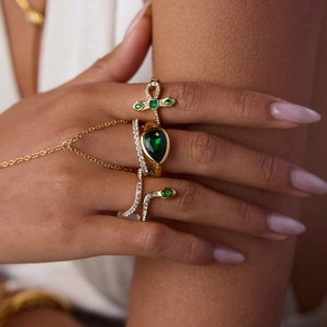 Close-up of gold-plated rings set featuring green zircon teardrop and snake design jewelry