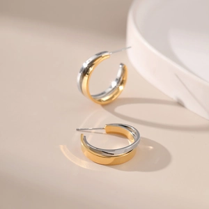 Minimalist two-tone gold and silver C-shaped metal stud earrings in a chic crossed design