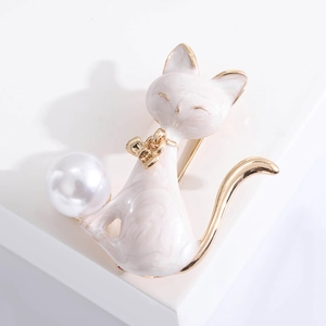 Detailed view of white enamel cat brooch with gold trim holding a large pearl accent