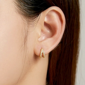 Elegant gold double-row pavé hoop earrings featuring white crystals on female model