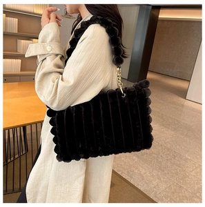 Detail of plush black tote bag featuring vertical stripes and gold chain shoulder strap