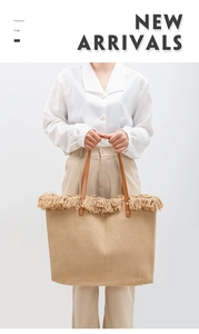 Detail of woven straw tote bag featuring decorative fringe and brown leather handles