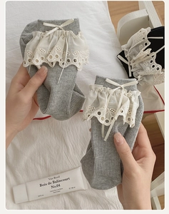 Close-up of grey lace trim socks featuring delicate white bows and ribbed cotton texture