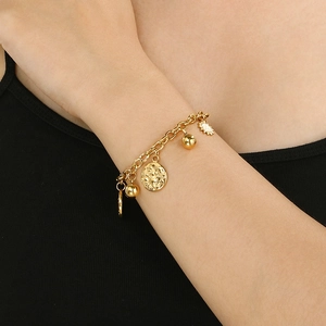 Detailed view of a gold-tone stainless steel sun charm bracelet on a model wrist