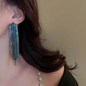 Detail of long fringe earrings with turquoise gradient rhinestones and metal chain