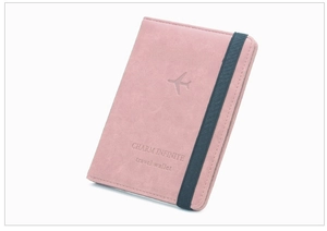 Close-up of pink faux leather passport holder with elastic band and airplane embossing
