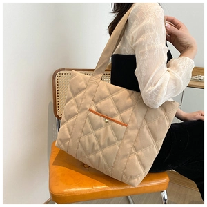 Close-up of khaki quilted canvas tote bag with front pocket and gold metal button