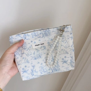 Detail of floral printed fabric bag with rabbit patterns and elegant pearl strap