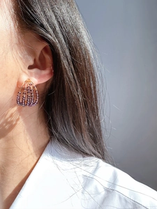 Detail of multi-layer purple crystal beaded earrings worn on a gold-plated C-shaped hoop