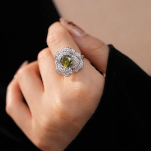 Detail of floral ring with olive green oval gemstone and micro-pave cubic zirconia crystals
