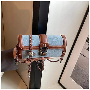 Detail of blue denim cylinder bag with crystal studs and leather strap chain