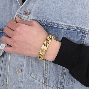 Detail of gold skull Cuban link bracelet worn on wrist with denim jacket background