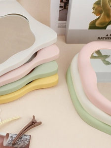 Detail view of wavy cloud-shaped makeup mirrors in pastel white, pink, green, and yellow