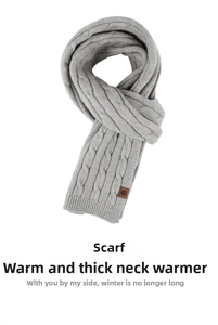 Close-up of light grey knit scarf with cable texture and brown snowflake leather tag