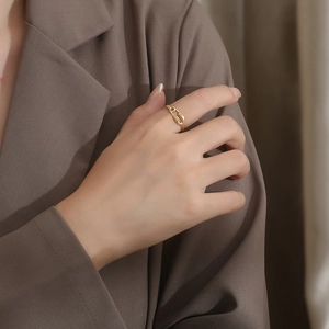 Close-up of a gold paperclip chain ring on a finger with professional lighting
