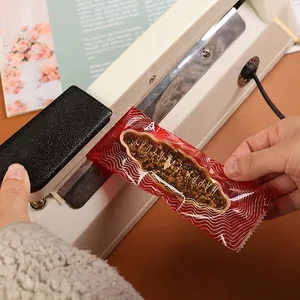 Manual white heat sealer with black handle sealing a patterned plastic food bag