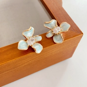 Vue détaillée des boucles d'oreilles fleur bleu clair avec bordure dorée et cristal