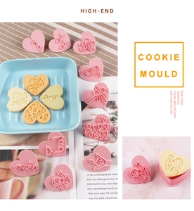 Pink heart and LOVE letter cookie molds with finished yellow biscuits for baking