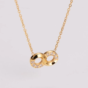 Close-up of golden infinity pendant with sparkling crystals on a fine link chain