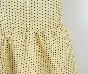 Detail of yellow polka dot dress showing waist pleats and light chiffon fabric texture